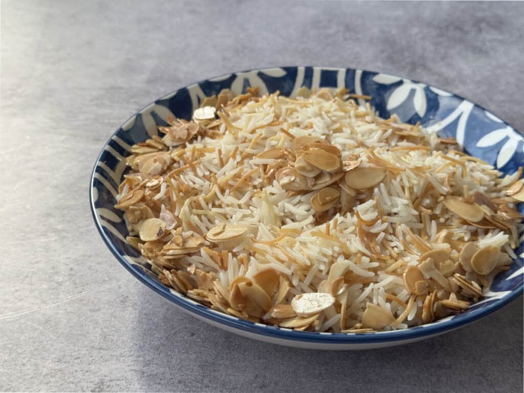 Side view of a bowl of Armenian rice pilaf with vermicelli and toasted almonds.