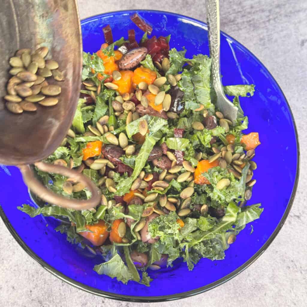 Tossing roasted butternut squash and gigante bean salad in a large bowl.
