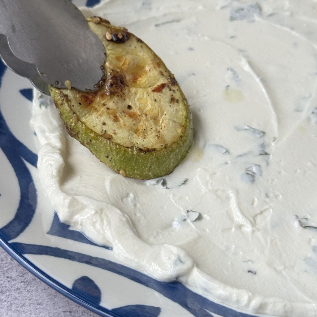 Plating broiled zucchini over swirled lebneh.