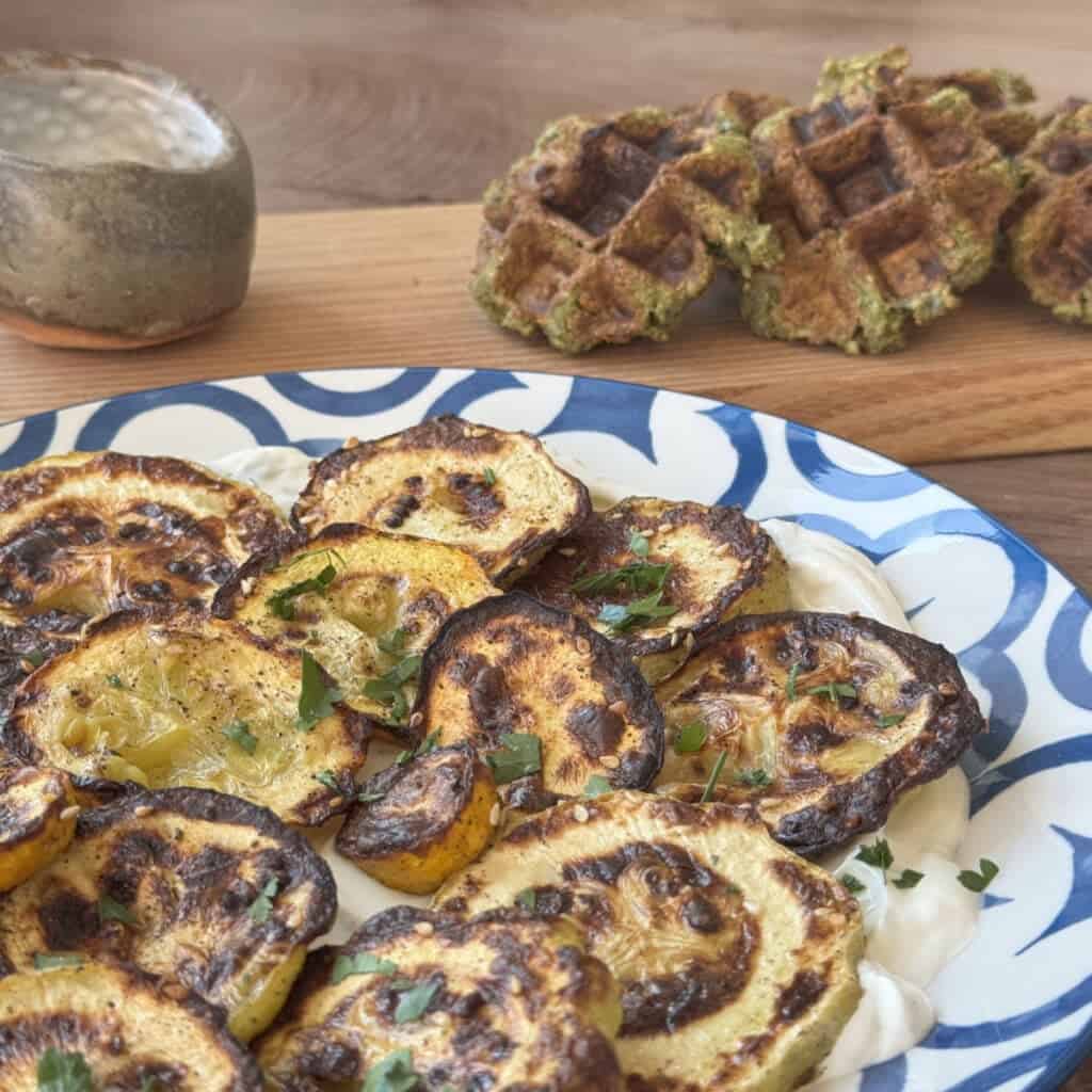 Broiled zucchini plated over swirled lebneh and falafel waffles.
