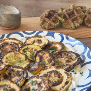 Broiled zucchini plated over swirled lebneh and falafel waffles.