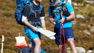 1. Two male hikers checking a map during outdoor trekking adventure with backpacks and hiking gear.