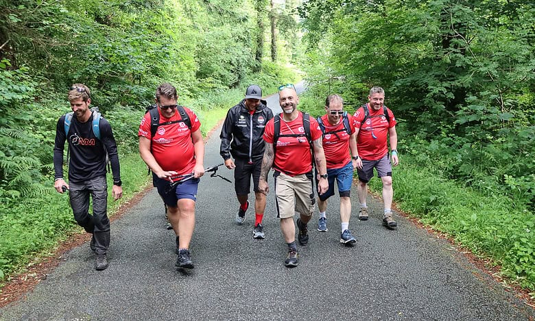 Group of hikers walking through lush forest during outdoor adventure.