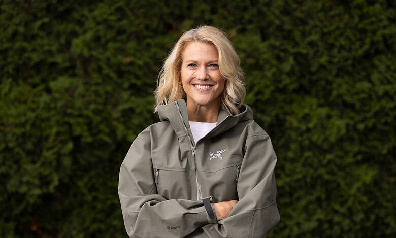 1. Woman in outdoor waterproof jacket smiling, lush green background.
