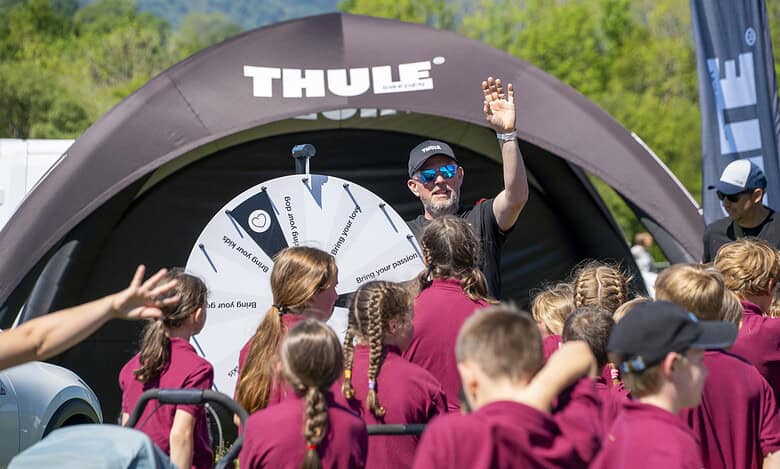 Outdoor Insight showcasing Thule products at a mountain festival with a group of children.