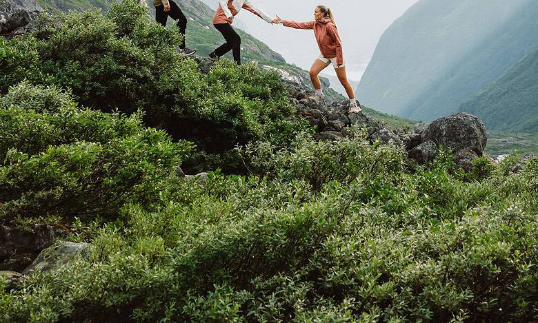 Family hiking in scenic mountain terrain with lush greenery and snow-capped peaks.