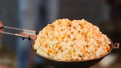 Popcorn served in a black bowl at an outdoor event, with people and warm lighting in the background.