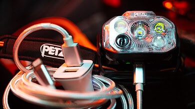 Petzl headlamp with charging cable and accessories for outdoor activities.