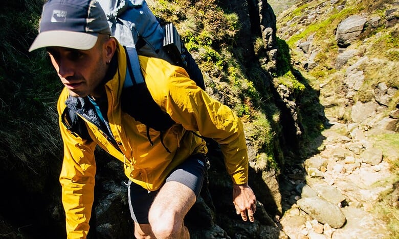 Man hiking on rocky trail with backpack in outdoor landscape.