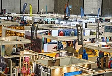 Indoor outdoor gear trade show with various booths and visitors.