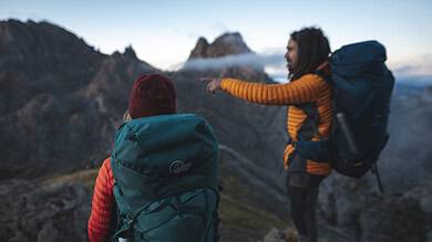 Two hikers with backpacks enjoying mountain views in outdoor gear.