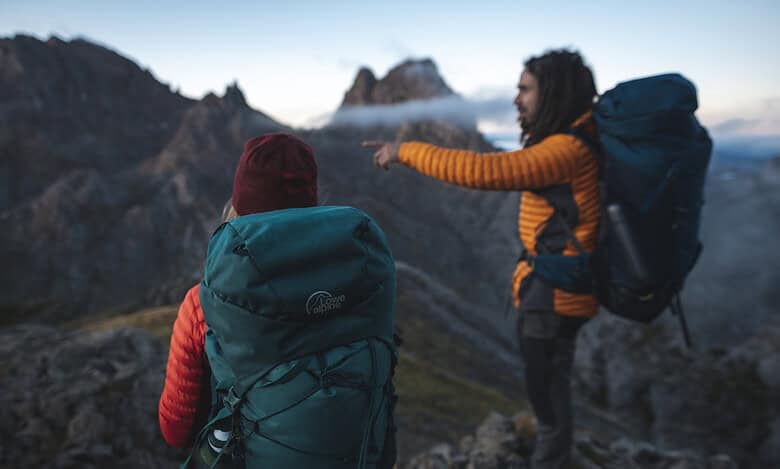 Two hikers with backpacks enjoying mountain views in outdoor gear.