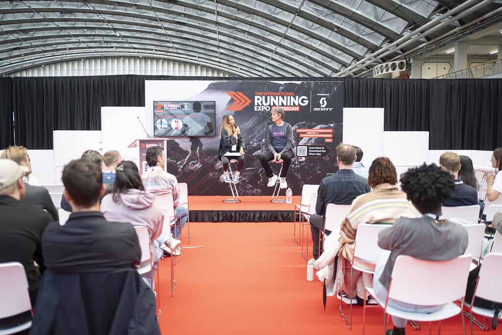 Running expo with speakers and audience in a large indoor venue.
