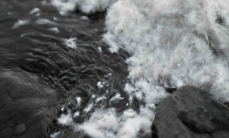 Close-up of water flowing over rocks with foam and bubbles.