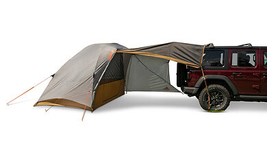 Camping tent attached to a vehicle for outdoor adventure.