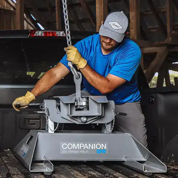 Man installing a 5th wheel hitch in a truck bed.