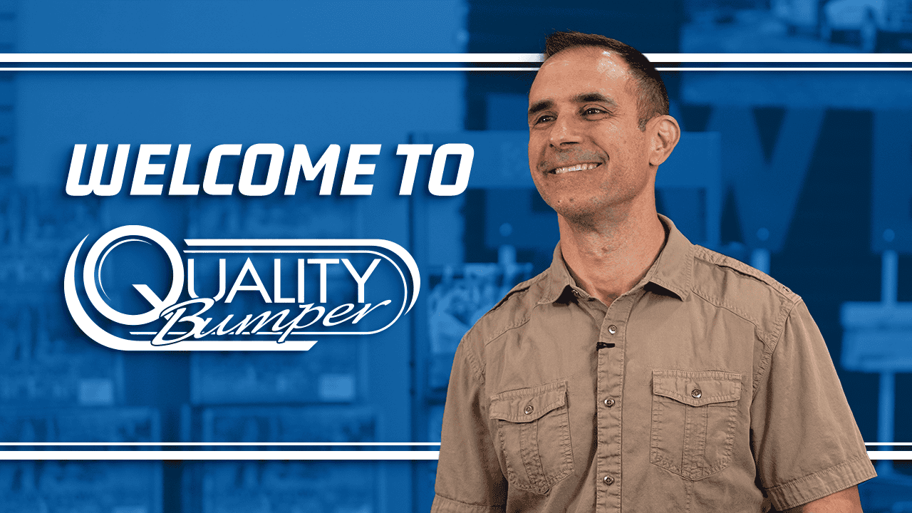Slender man with short, dark hair and a tan work shirt with blue background that features, "Welcome to Quality Bumper"
