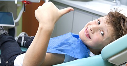 Smiling child giving a thumbs up in a dental chair, fluoride treatment for kids in Leesburg VA