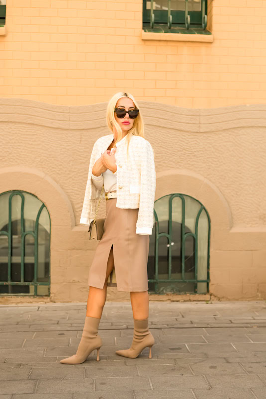 Look de calle con chaqueta de tweed crema, falda midi beige y botines a juego de Stylicious
