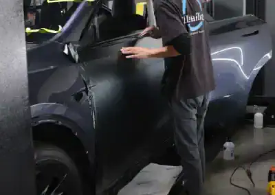 Technician applying paint protection film to vehicle fender