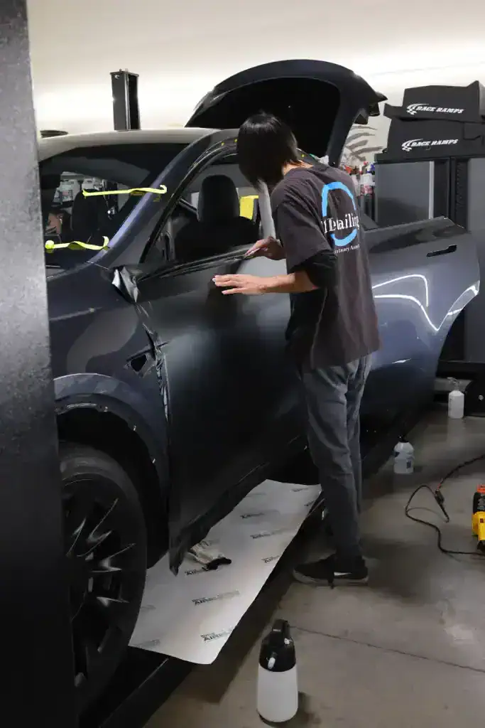 Technician applying paint protection film to vehicle fender