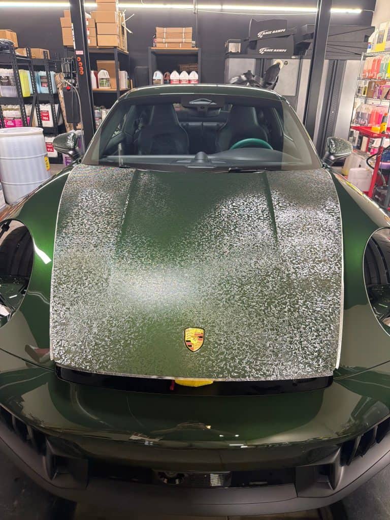Green Porsche with detailed hood in auto shop for premium car care.