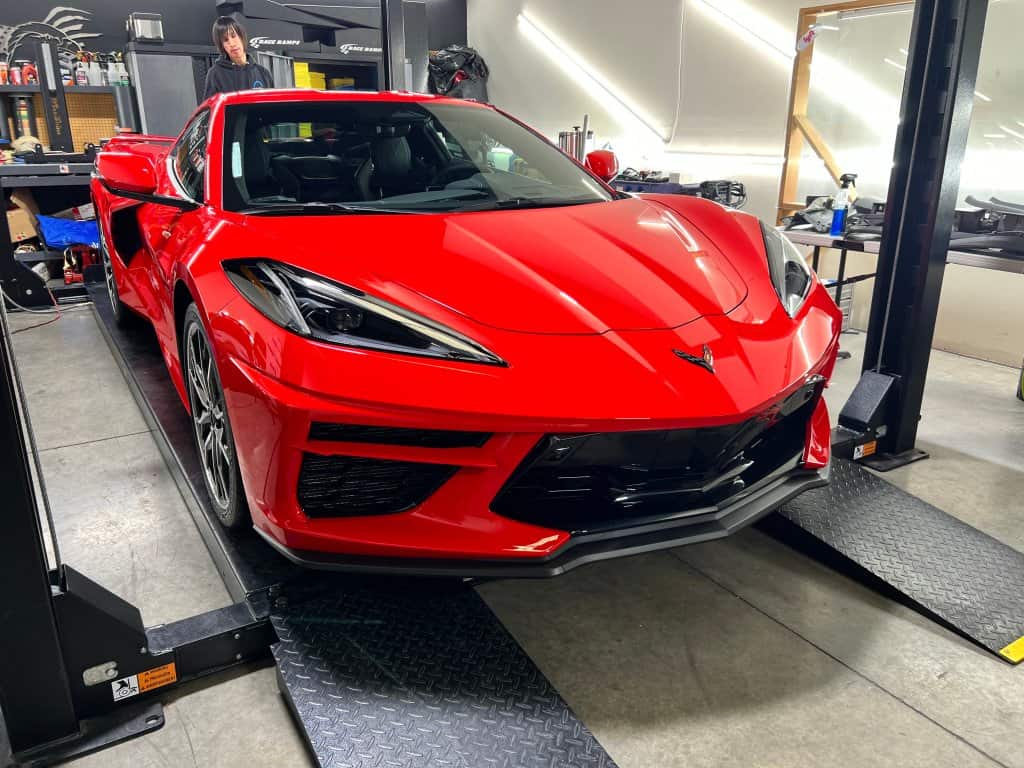 Red Chevrolet Corvette on a car lift at T1Detailing workshop.