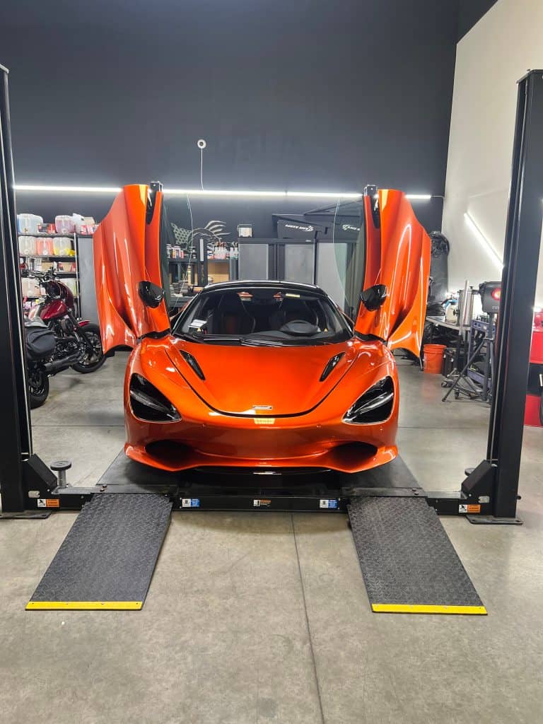 Orange sports car with open doors on a car lift at T1Detailing.