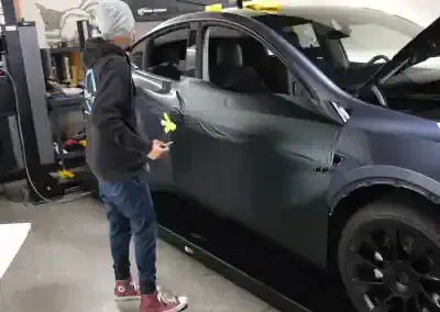 Technician applying paint protection film to black SUV