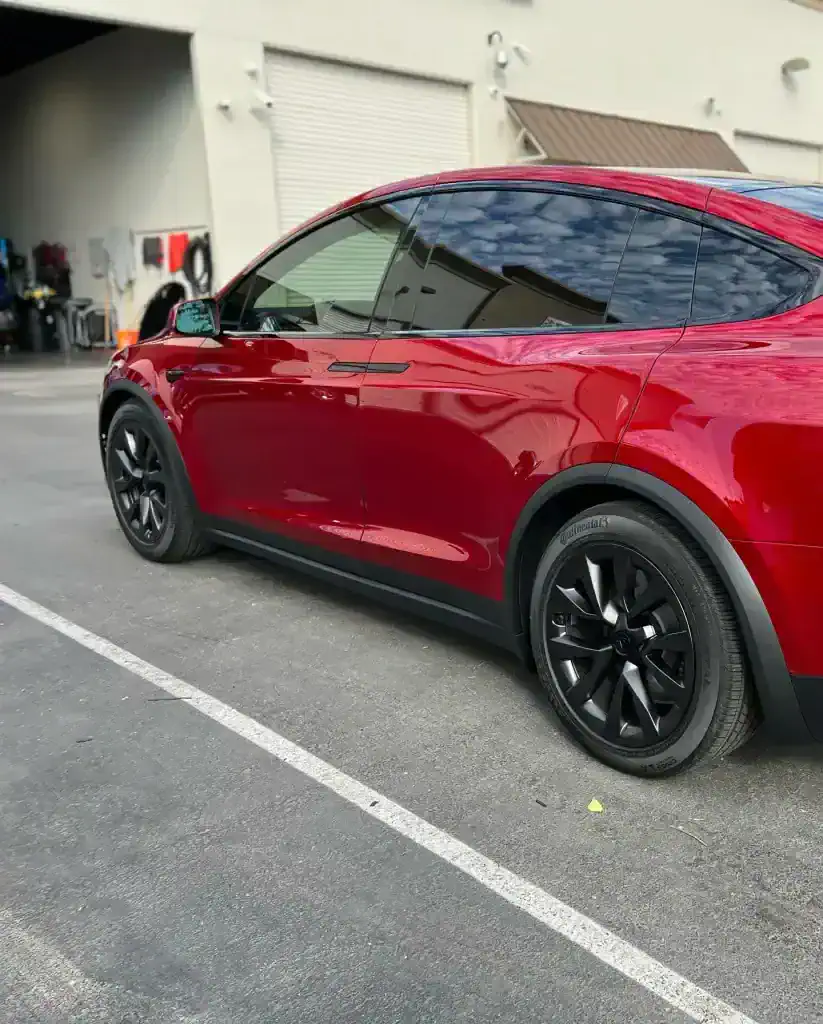 Red Tesla Model Y parked outside T1Detailing for professional car detailing.