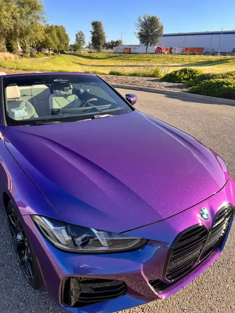 Purple BMW convertible parked outdoors with a scenic background.