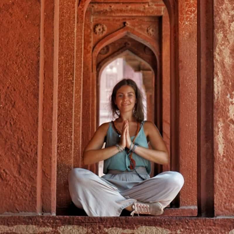 Donna che pratica yoga e meditazione in un luogo storico in India.