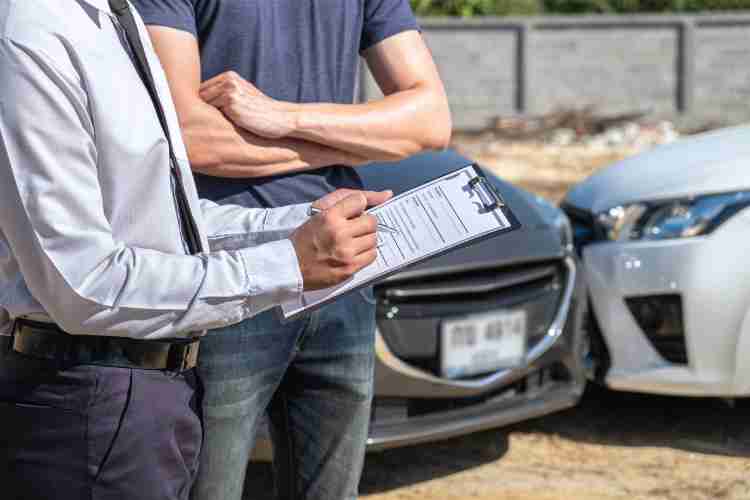 A picture of a car accident scene with a person taking notes, illustrating what to do in a car accident