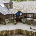 Bright and welcoming childcare centre with outdoor play area at Thrive Childcare, featuring a courtyard, garden space, and cosy building with large windows for a nurturing early education environment.