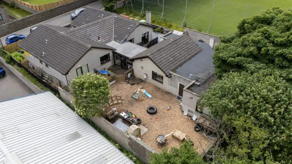 Bright and safe outdoor play area at Thrive Childcare featuring playground equipment, tires, sandpit, and activity stations within a secure enclosed yard.