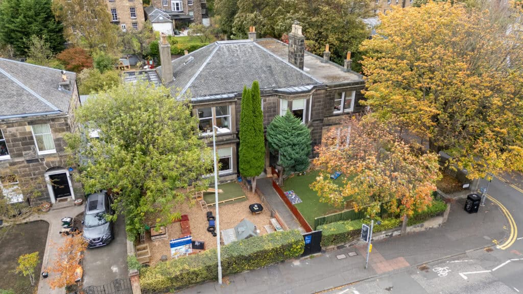 Bright outdoor play area at Thrive Childcare with colourful toys, trees, and a safe environment for children’s outdoor activities in a garden setting.