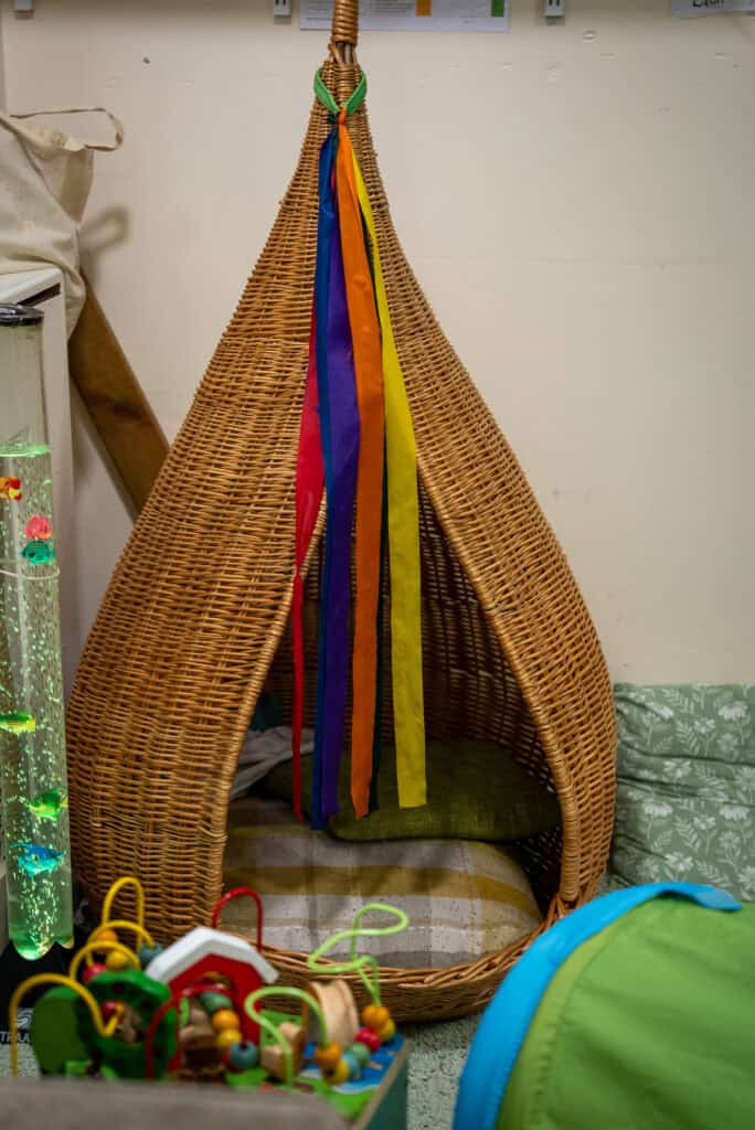A wicker tepee with colourful ribbons and a green cushion, creating a fun and inviting space for children to play and relax at Thrive Childcare, Holyrood Nursery Princes Dock.