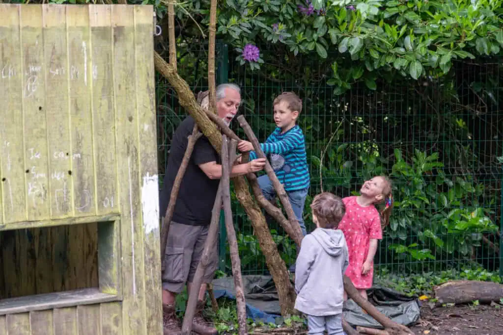 Aerial view of children and caretaker engaging in outdoor creative play at Thrive Childcare, encouraging imagination and social development in a safe, natural environment.