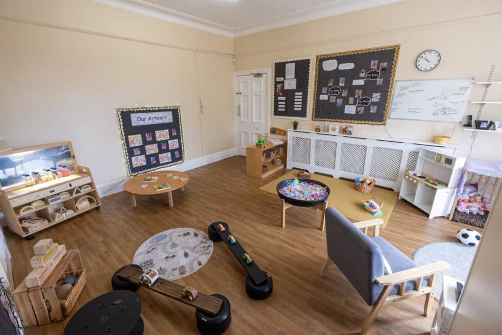 Bright and welcoming childcare room at Thrive Childcare featuring educational displays, toys, and comfy seating for children’s learning and play activities, creating a safe environment for early childhood development.