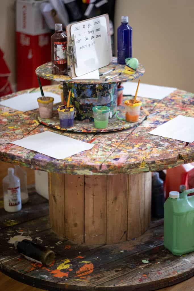 Bright nursery art table with paint supplies and paper for creative preschool activities at Thrive Childcare.