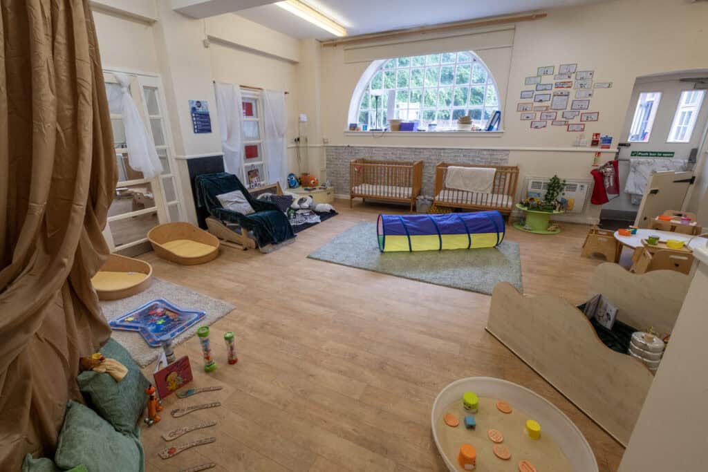 Bright indoor childcare playroom with toys, activity stations, and soft mats, designed for early childhood development at Thrive Childcare. Safe, engaging environment for young children to learn and play.