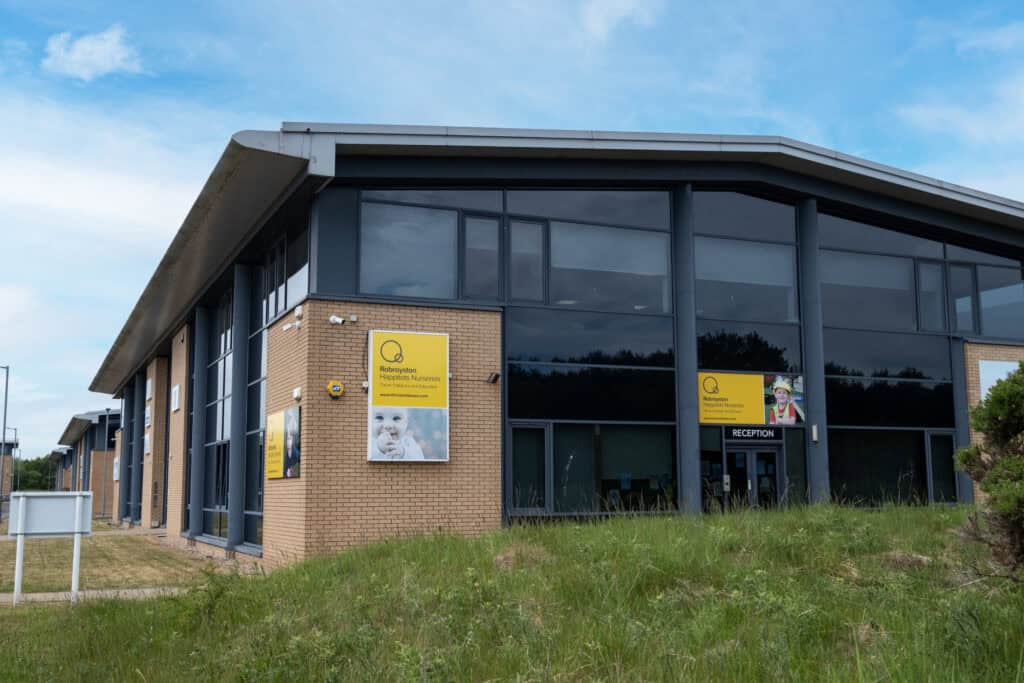 Bright modern childcare centre with large glass windows and yellow signage for Thrive Childcare and Nursery, offering a safe, engaging environment for children’s early education and development.