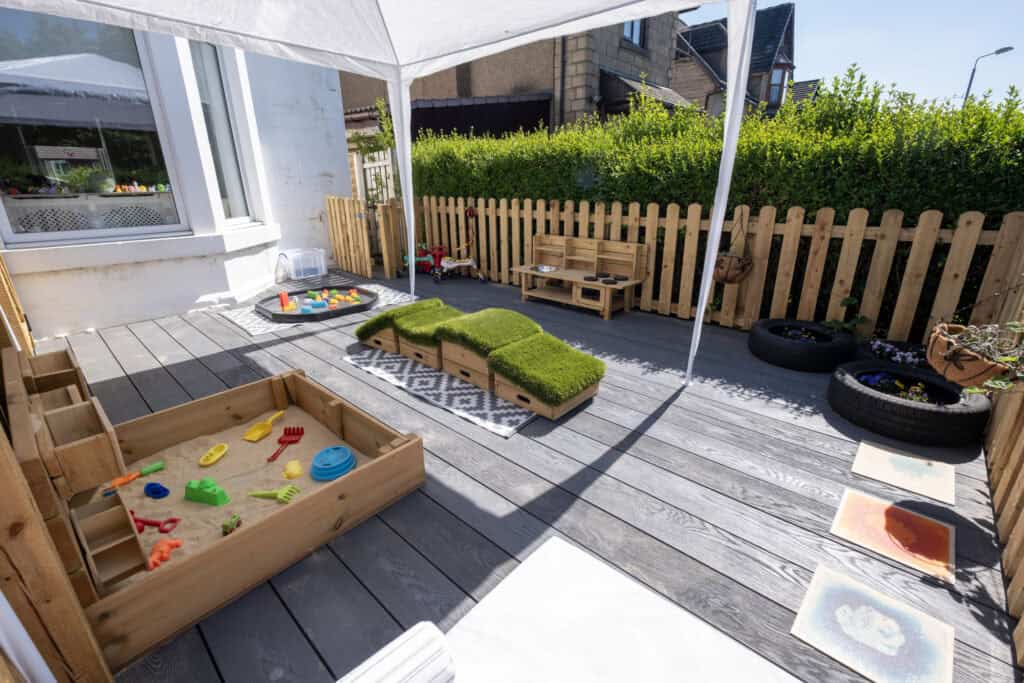 Bright outdoor childcare play area at Thrive Childcare with toys, sandbox, and seating, ideal for children's development and fun in a safe, supervised environment.