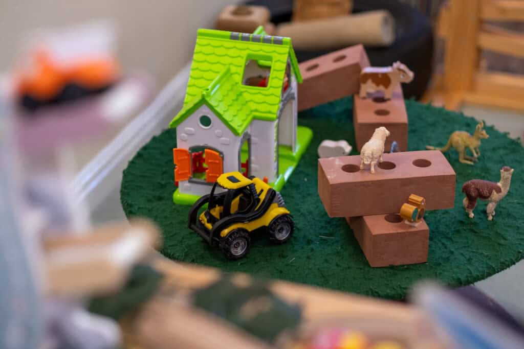 Colourful toy farm playset with animals, bricks, and a small yellow vehicle, highlighting childcare activities and imaginative play at Thrive Childcare.