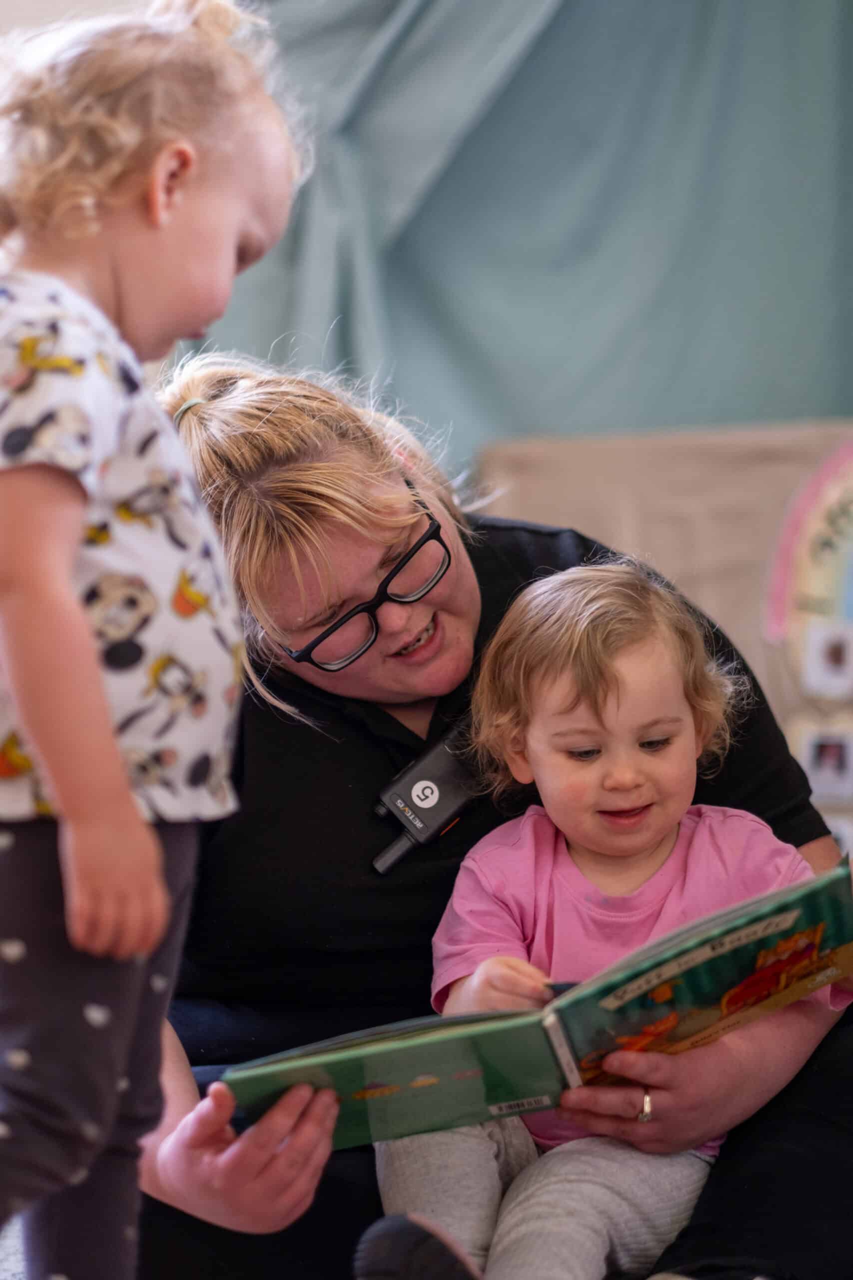 Bright, caring childcare worker engaging with young children in a nurturing environment at Thrive Childcare, promoting early childhood development and learning.