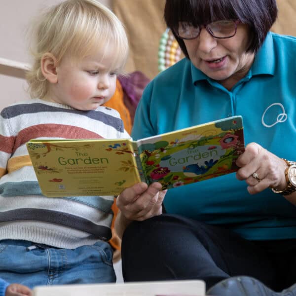1. Caregiver reading a colourful children's book to a young child at Thrive Childcare, fostering early literacy and development.