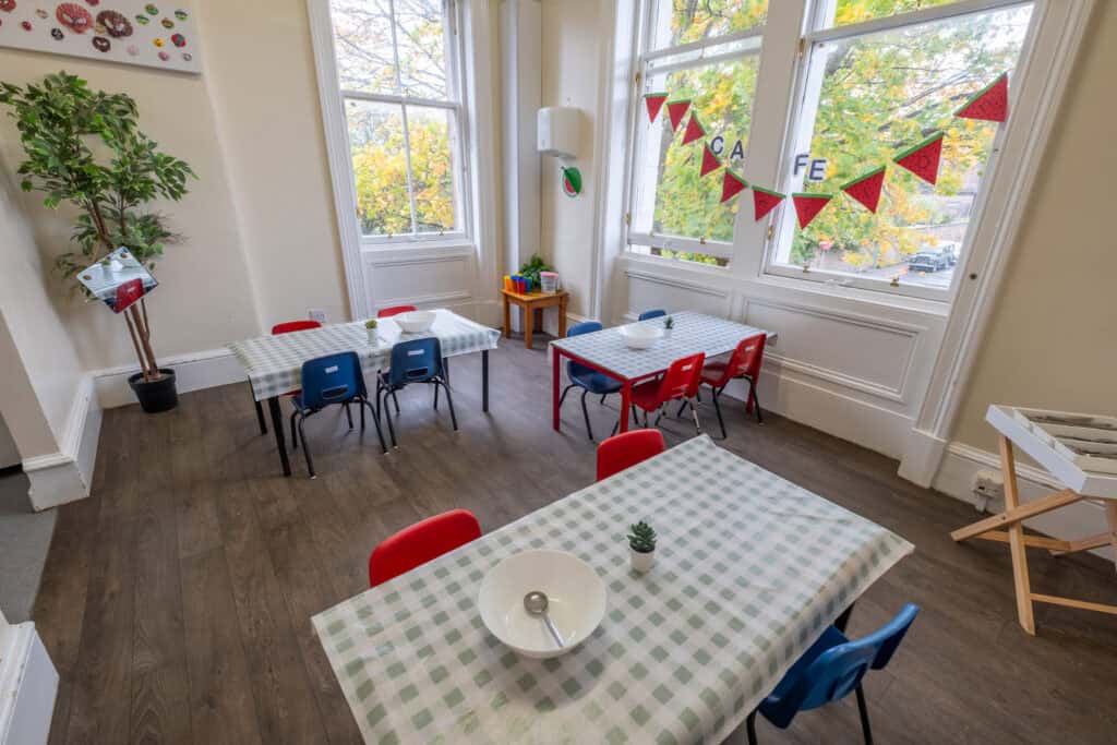 Bright, welcoming childcare room with large windows, colourful decorations, and child-sized tables and chairs, perfect for early childhood development and fun learning at Thrive Childcare.