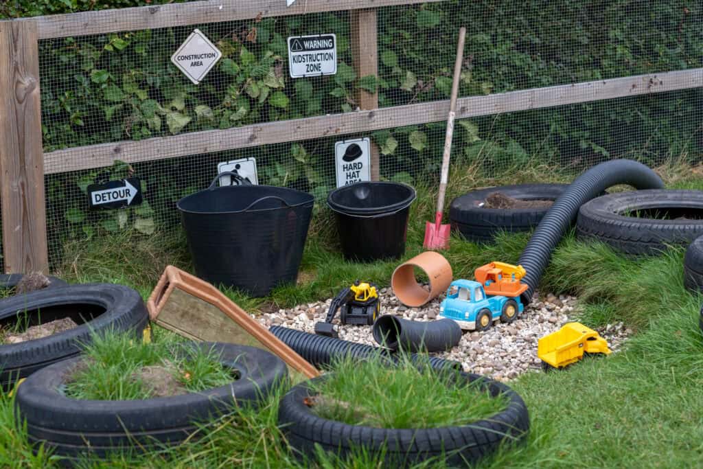 Bright outdoor toddler play area at Thrive Childcare with construction-themed toys, tyres, and safety signs, promoting child development and outdoor exploration in a safe environment.
