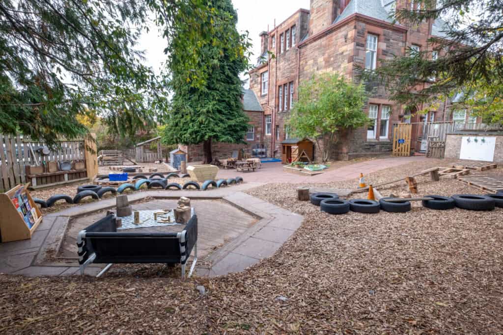 1. Safe outdoor play area at Thrive Childcare with tire obstacle courses and natural playing spaces for children’s development and outdoor learning.