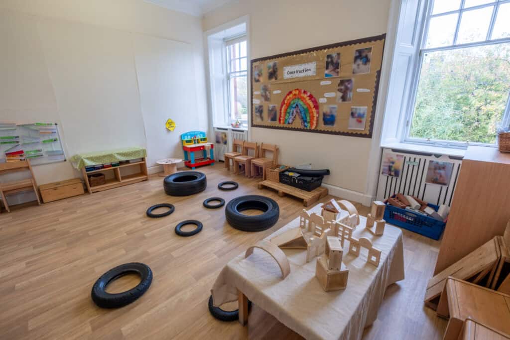 Bright early childhood classroom with wooden toys, tyres, and art display, designed for nurturing young children's development at Thrive Childcare, promoting learning, creativity, and fun in a safe environment.